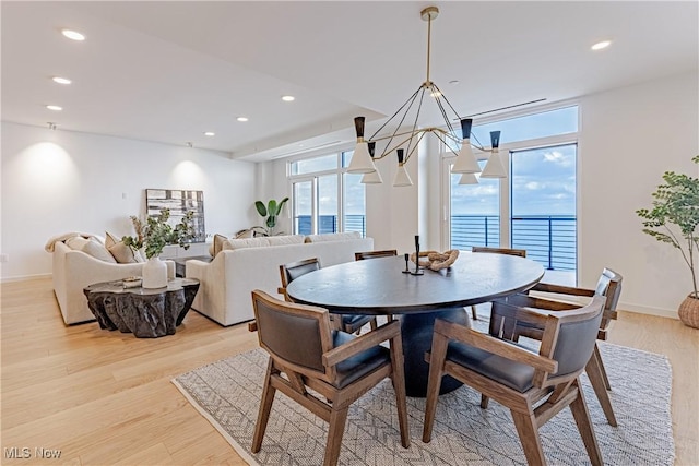 dining area featuring a chandelier, light wood-type flooring, and a water view