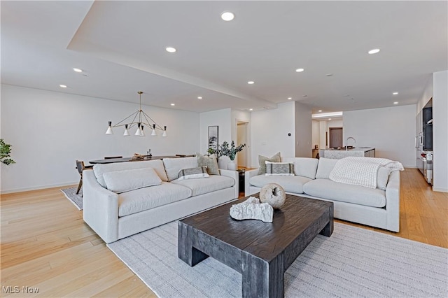 living room featuring sink, a chandelier, and light wood-type flooring