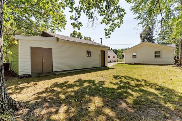 back of house with a yard and an outdoor structure