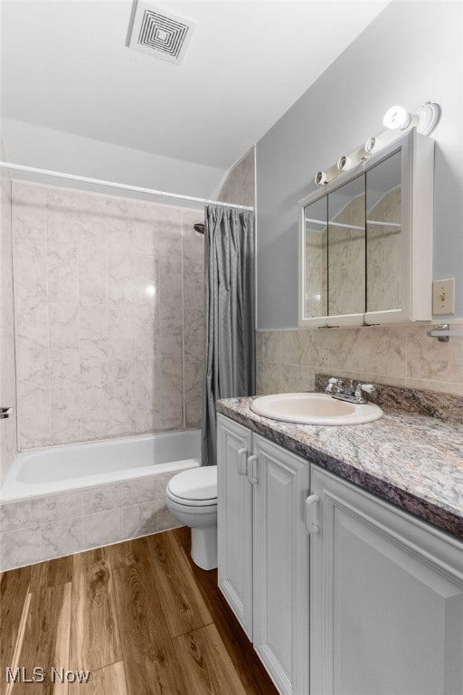 full bathroom featuring shower / bath combo with shower curtain, toilet, hardwood / wood-style flooring, and vanity