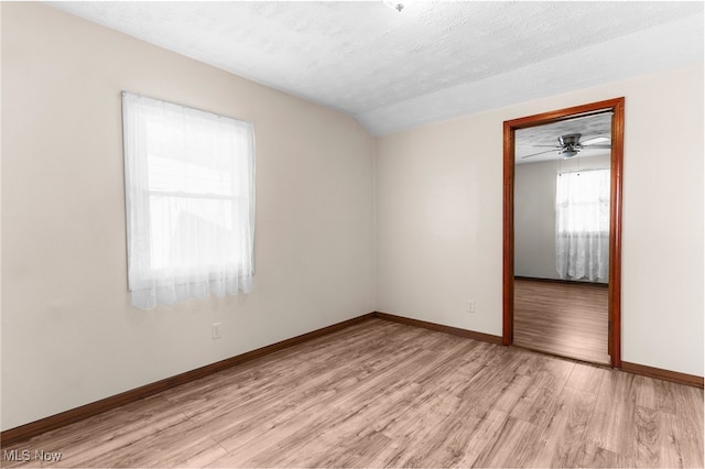 unfurnished room featuring a textured ceiling, ceiling fan, lofted ceiling, and light hardwood / wood-style floors