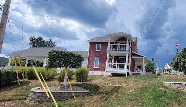 back of property featuring a yard, covered porch, and a balcony