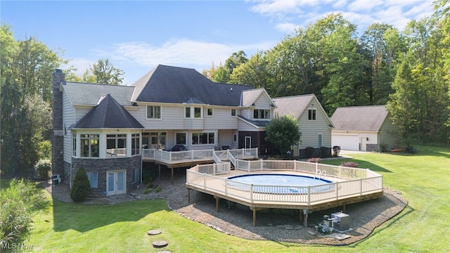 rear view of house with an outdoor structure, a garage, a lawn, and a wooden deck