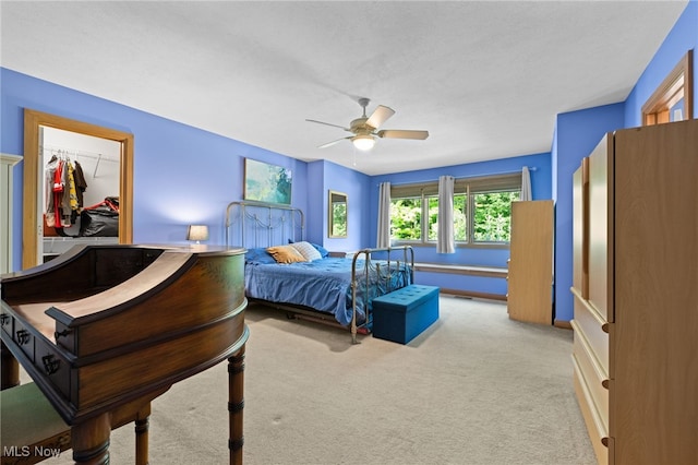 carpeted bedroom with a closet, ceiling fan, and a spacious closet