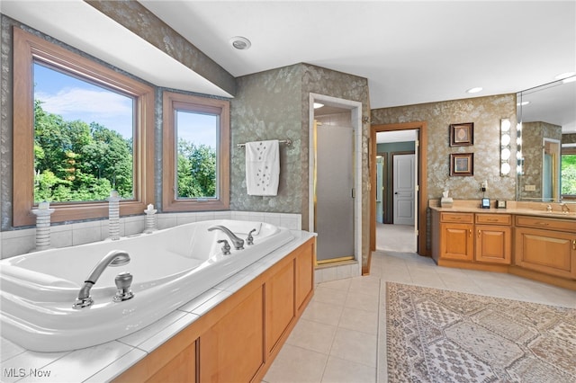 bathroom with tile patterned flooring, independent shower and bath, vanity, and a healthy amount of sunlight