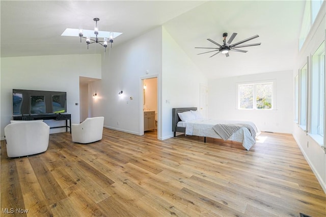 bedroom featuring high vaulted ceiling, light hardwood / wood-style floors, connected bathroom, and an inviting chandelier