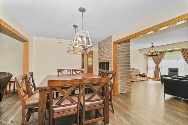 dining room with hardwood / wood-style flooring and a brick fireplace