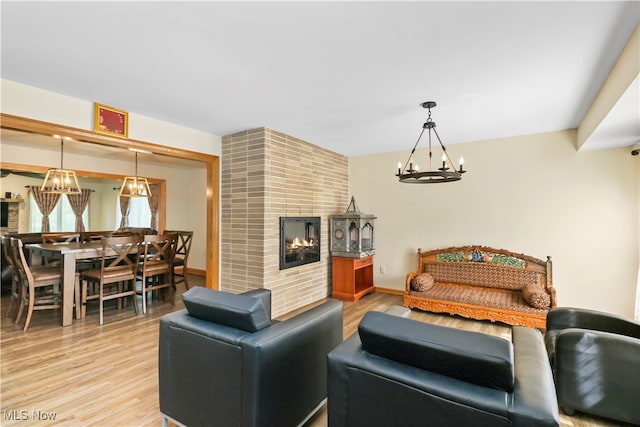 living room with light wood-type flooring, a fireplace, and a chandelier