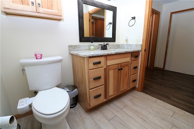 bathroom with toilet, hardwood / wood-style flooring, and vanity