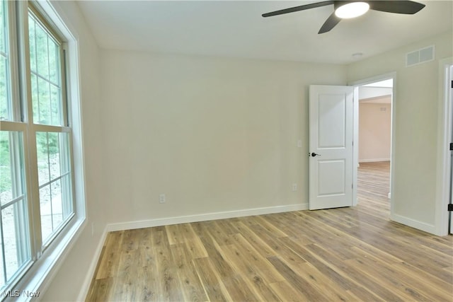 empty room featuring a wealth of natural light, light hardwood / wood-style flooring, and ceiling fan