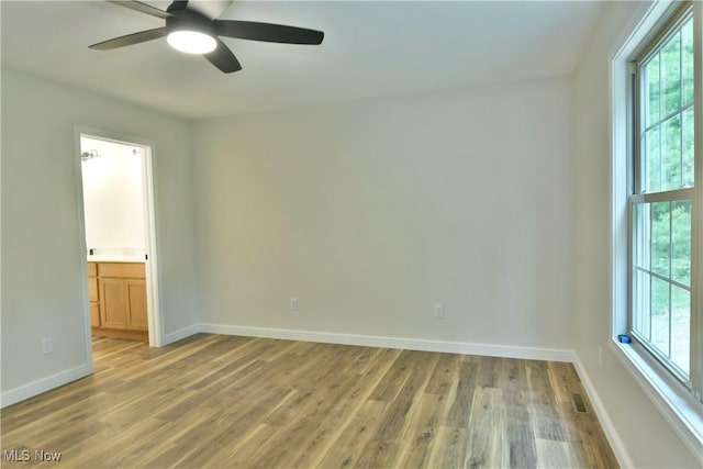 spare room with ceiling fan, wood-type flooring, and a healthy amount of sunlight