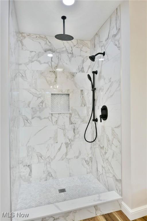 bathroom featuring hardwood / wood-style floors and a tile shower