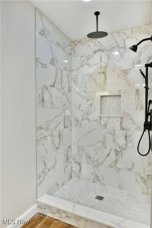 bathroom featuring tiled shower and wood-type flooring