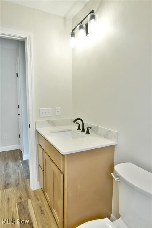 bathroom with vanity, toilet, and hardwood / wood-style floors