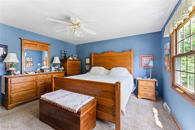 bedroom with light colored carpet, multiple windows, and ceiling fan