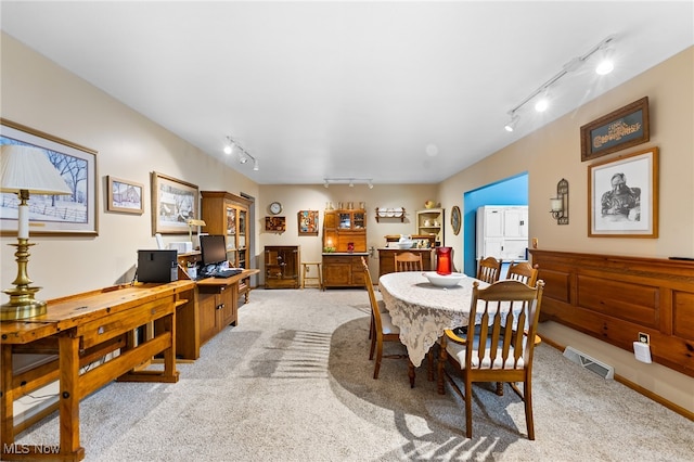 dining area featuring rail lighting and light colored carpet