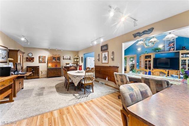 dining space with hardwood / wood-style floors and track lighting