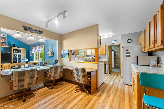 kitchen with kitchen peninsula, plenty of natural light, track lighting, and light wood-type flooring