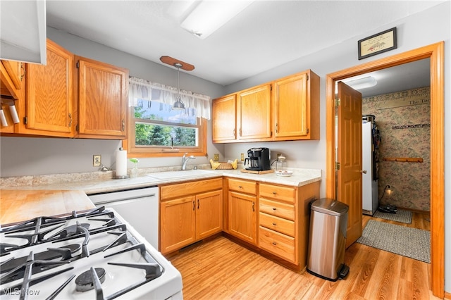 kitchen featuring sink, white appliances, decorative light fixtures, and light wood-type flooring