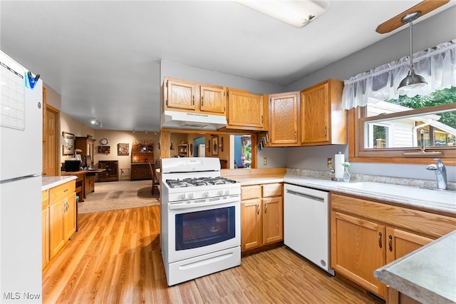 kitchen with sink, kitchen peninsula, light hardwood / wood-style floors, decorative light fixtures, and white appliances