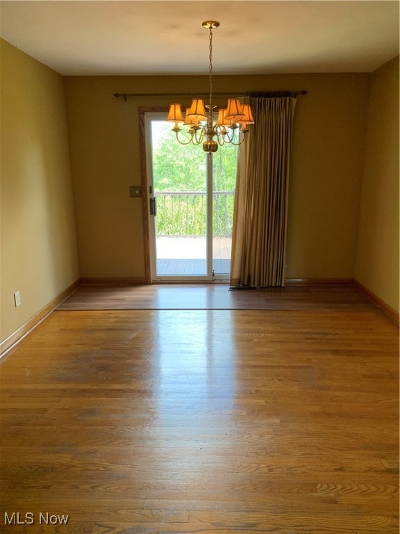 unfurnished room with a notable chandelier and wood-type flooring