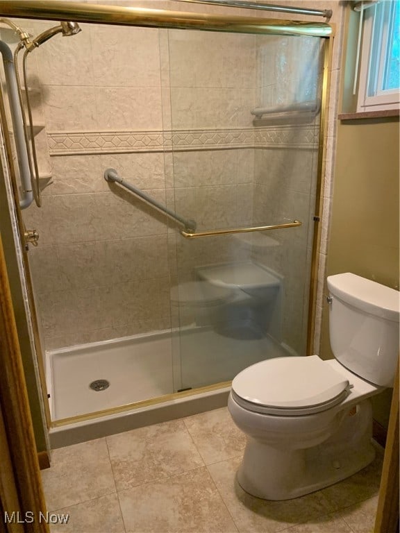 bathroom with toilet, tile patterned floors, and an enclosed shower