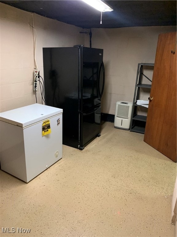 basement featuring black refrigerator and white refrigerator