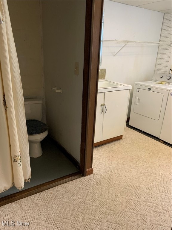 laundry room featuring washer and clothes dryer and light carpet