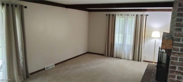 carpeted empty room featuring beam ceiling