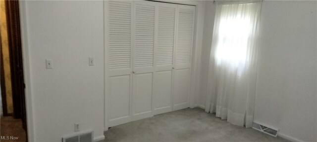 unfurnished bedroom with light carpet and a closet