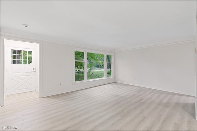 spare room with crown molding, a wealth of natural light, and light hardwood / wood-style floors