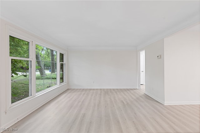 empty room with crown molding and light hardwood / wood-style flooring