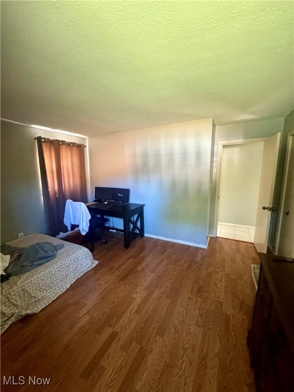 bedroom with dark hardwood / wood-style floors and a textured ceiling