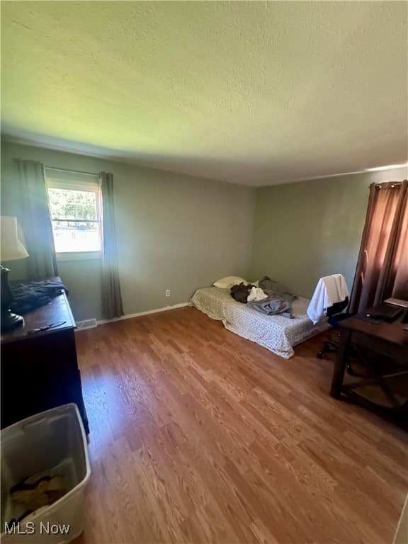 bedroom with a textured ceiling and hardwood / wood-style flooring