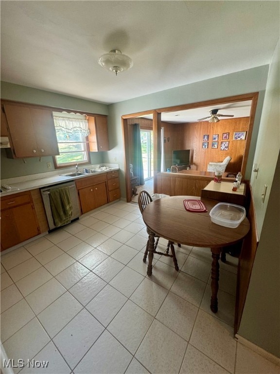 dining area featuring ceiling fan, light tile patterned floors, wooden walls, and sink