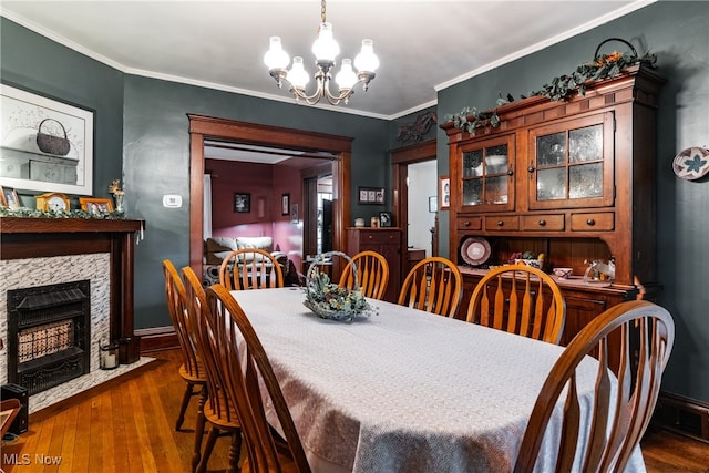 dining room with dark wood-type flooring, an inviting chandelier, and ornamental molding