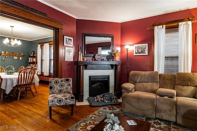 living room with hardwood / wood-style flooring, a fireplace, a healthy amount of sunlight, a chandelier, and ornamental molding