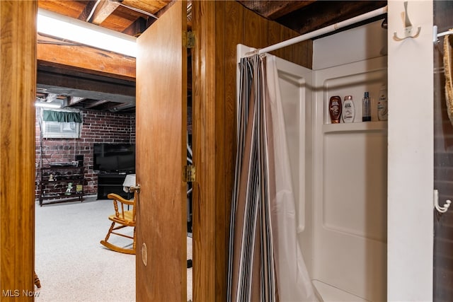 bathroom with walk in shower and brick wall