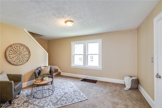 living area with a textured ceiling and carpet