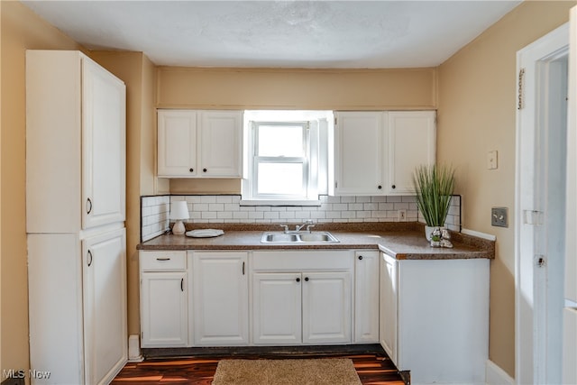 kitchen with hardwood / wood-style floors, decorative backsplash, white cabinets, and sink