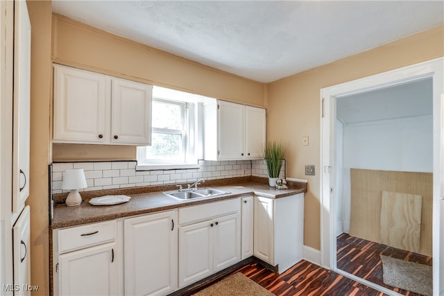 kitchen featuring sink, backsplash, dark hardwood / wood-style flooring, and white cabinets