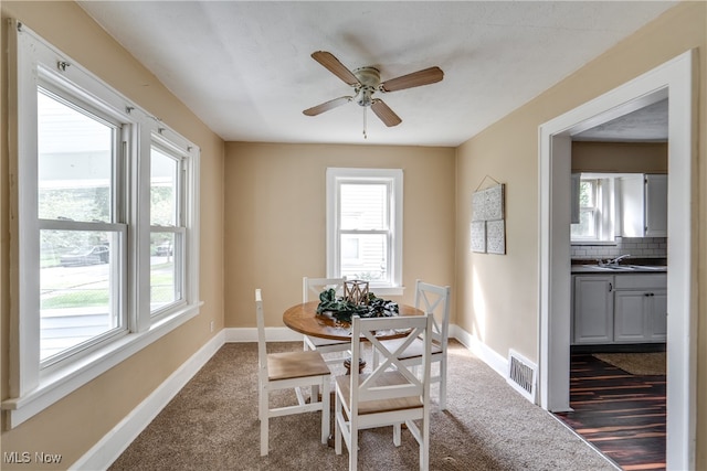 dining space with dark hardwood / wood-style flooring, sink, and ceiling fan