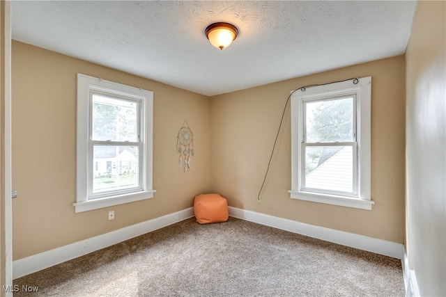 carpeted empty room featuring a textured ceiling