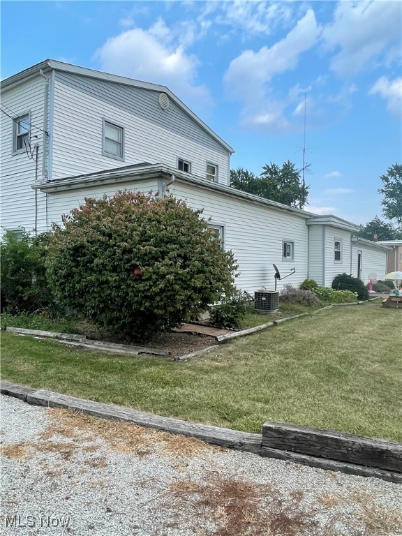 view of side of property featuring a yard and cooling unit