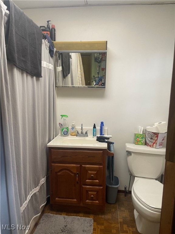 bathroom with walk in shower, toilet, parquet flooring, and vanity