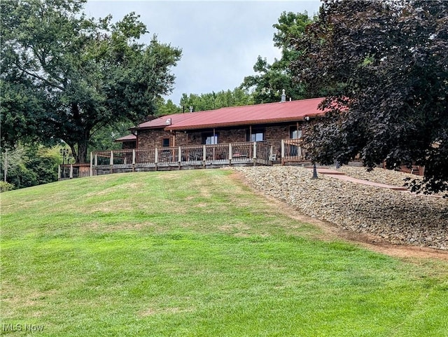 exterior space with a yard, brick siding, and metal roof