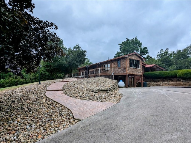 view of front facade with a wooden deck and driveway