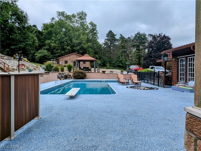 view of swimming pool featuring a gazebo, a diving board, and a patio