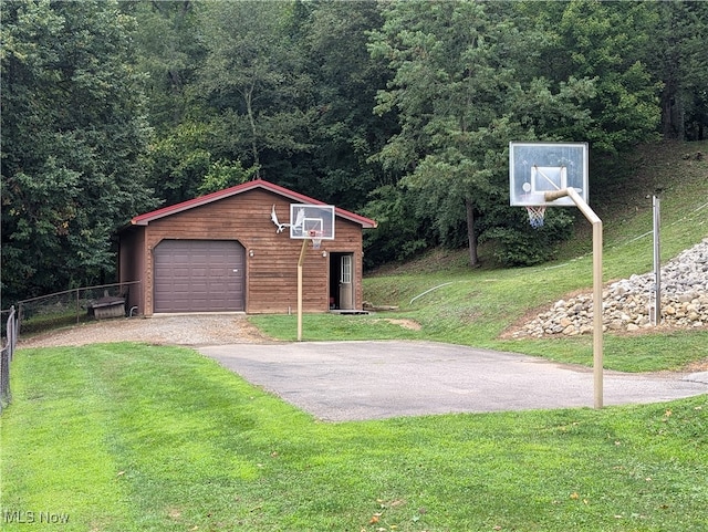 view of front of home featuring basketball court, an outdoor structure, a garage, and a front yard