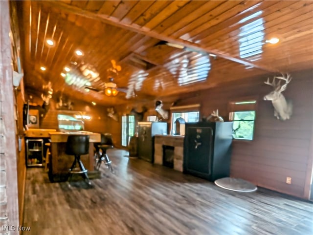 interior space with wooden walls, dark hardwood / wood-style floors, vaulted ceiling, and wooden ceiling